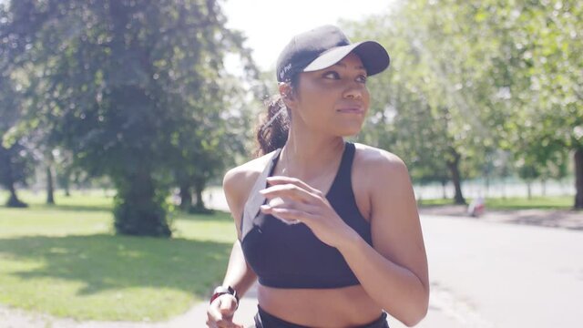 Attractive young female jogging in a park on a sunny day, in slow motion