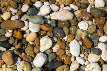 Abstract pebble background. Multi-colored stones on the Black Sea coast. Selective focus in the center of the frame