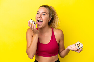 Girl with curly hair isolated on yellow background eating a donut