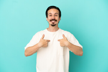 Young caucasian man isolated on blue background with surprise facial expression