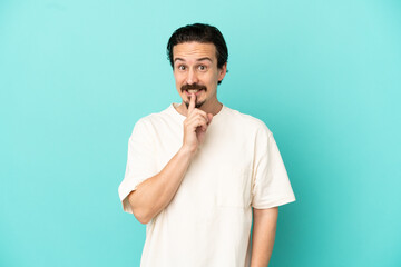 Young caucasian man isolated on blue background showing a sign of silence gesture putting finger in...