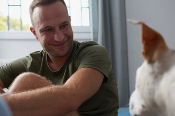 Man with a brown and white american staffordshire terrier dog in a home