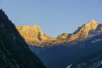 Naklejka na ściany i meble golden color of mountain peaks at sunrise in triglav nationalpark, slovenia