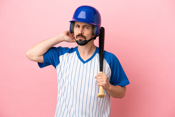 Young caucasian man playing baseball isolated on pink background having doubts