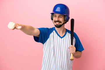 Young caucasian man playing baseball isolated on pink background giving a thumbs up gesture