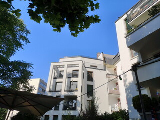 Moderne weiße Architektur mit teuren Eigentumswohnungen vor blauem Himmel im Sommer neben einer...
