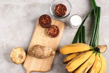 Top View Ingredient Preparation making Banana and Sweet Potato Compote (Kolak Pisang Ubi). Ripe Banana, Sweet Potato, Palm Sugar (Gula Merah), Pandan Leaves, and Coconut Milk. 