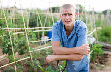 Fototapeta premium Portrait of man standing and holding handle of shovel in kitchen garden