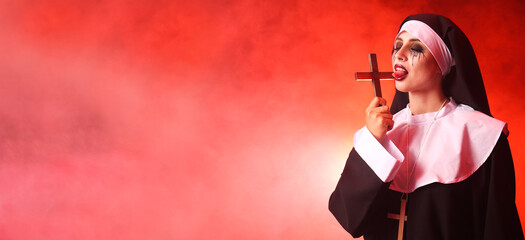 Woman dressed for Halloween as nun with cross on color background