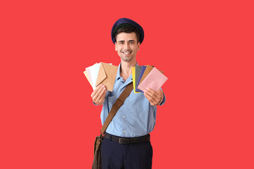 Handsome young postman with letters on color background