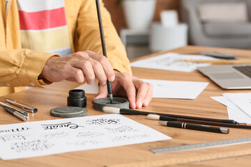 Young male calligrapher with ink at home, closeup