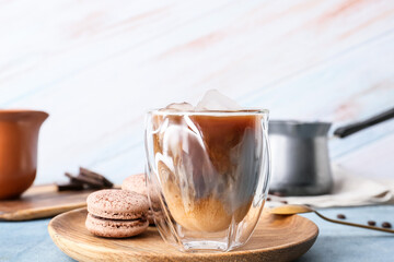 Plate with glass of tasty iced coffee and macaroons on table