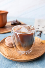 Plate with glass of tasty iced coffee and macaroons on table
