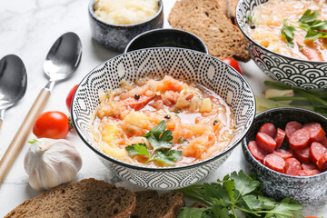 Bowl with tasty sauerkraut soup and ingredients on light background