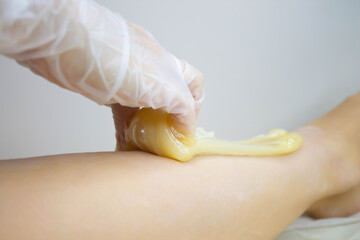The sugaring master applies the paste to the legs. - obrazy, fototapety, plakaty