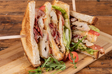 a delicious club house sandwich with chicken, bacon and lettuce and tomato on a wooden board
