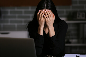 Young depressed businesswoman in dark office