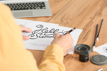 Young male calligrapher working at home, closeup