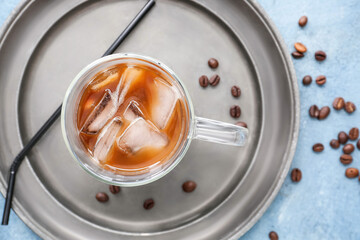 Plate with glass cup of tasty iced coffee on color background