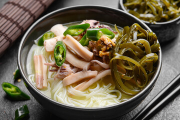 Tasty Chinese soup in bowl on dark background, closeup