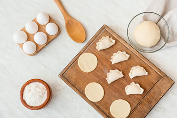 Composition with raw dumplings on light background