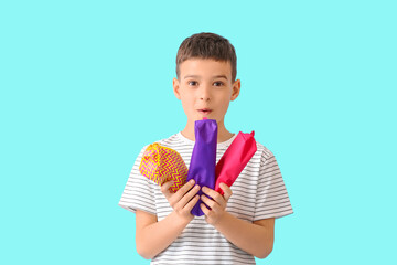 Little boy with pencil cases on color background