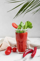 Composition with glass of bloody mary cocktail, vegetables and palm leaf on table