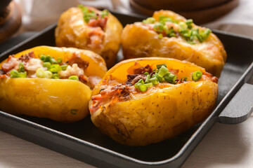 Frying pan with baked potato on table, closeup