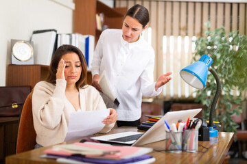 Outraged business woman expressing dissatisfaction with work of confused secretary in office