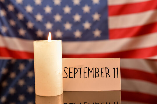 Paper with date of National Day of Prayer and Remembrance for the Victims of the Terrorist Attacks and candle against USA flag