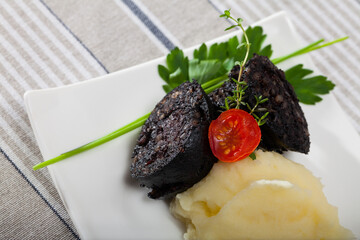 Dish of blood sausage with mashed potato served at plate with greens