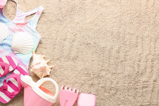 Set of beach accessories for children, stylish swimsuit and seashells on sand, closeup