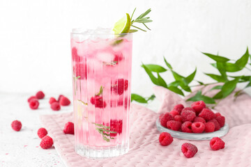 Fototapeta na wymiar Glass of tasty raspberry lemonade and berries on light background