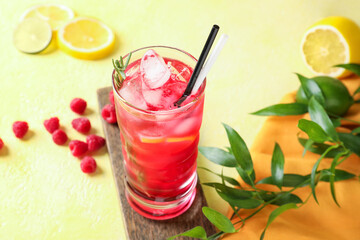 Glass of tasty raspberry lemonade on color background