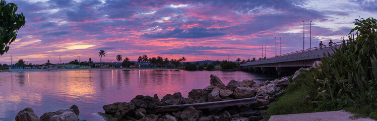 Panoramic view of the purple sunset sky over the peaceful bay and bridge; long exposure shot
