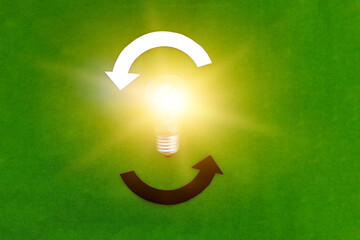 Electric light bulb, two round white and black arrows on a green background. The thought process, business ideas.