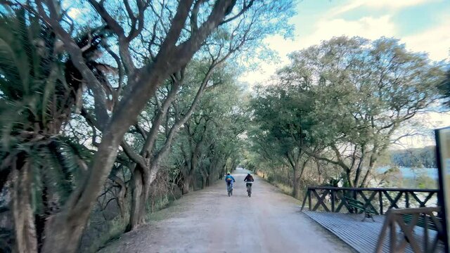 A Beautiful Dolly Shot Following Cyclists Along a Road in the Costanera Sur Ecological Reserve in Puerto Madero, Argentina.