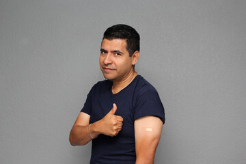 Happy Latino adult man shows his arm that just received the Covid-19 vaccine in the new normal for...