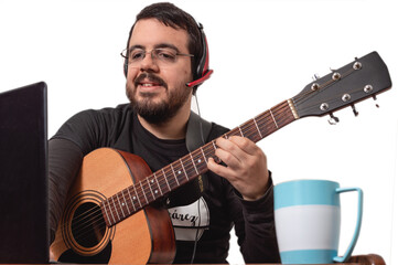 white adult latin bearded man with an acoustic guitar, glasses and headphones teaching online music...