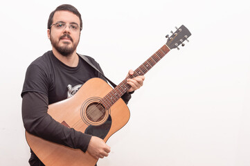 white adult latin male with beard and glasses posing holding his acoustic guitar against a white background