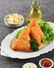 Vegetable Risoles with Triangle Shape. Thin Crepes Stuffed with Rogusa Corn, Carrot, and Green Bean, Served on White Plate with Cheese, Mayonaise, and Chilli Sauce. Copy Space on Grey Background