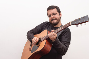 white hispanic latin man with beard and glasses inspired playing guitar with closed eyes and expression of pleasure in his face on white background