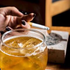 yellow cocktail drink with ice and background of hand with cigar from above