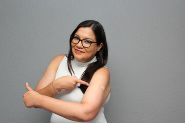 Happy Latina adult woman shows her arm that just received the Covid-19 vaccine in the new normal...
