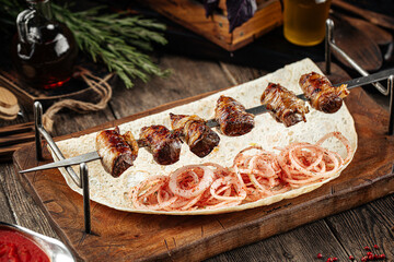 Caucasian beef liver in the shell shashlik skewers on a wooden background