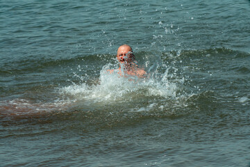 A man splashes merrily in the water of the sea.