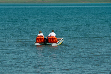A man and a woman on a catamaran in the middle of the lake.