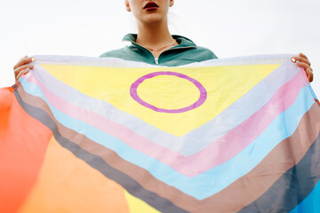 New international LGBTQ+ flag. Young woman with red lipstick on her lips holds rainbow flag, symbol...
