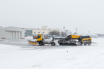 Airfield snow blowers cleaning the area near the airplane hangar at the airport in a severe blizzard