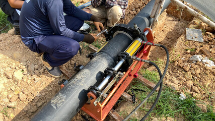 A plumber is working on plumbing with a hydraulic PE pipe welding machine for connecting pipes in a...